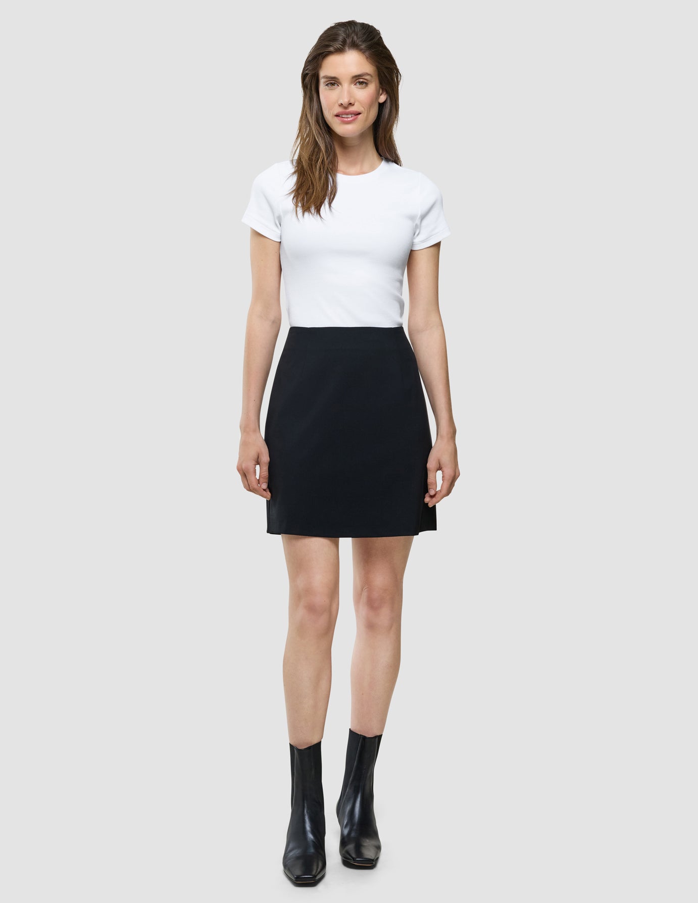 Ease Short Skirt i Black, helfigur på model med hvid t-shirt og sorte støvler.